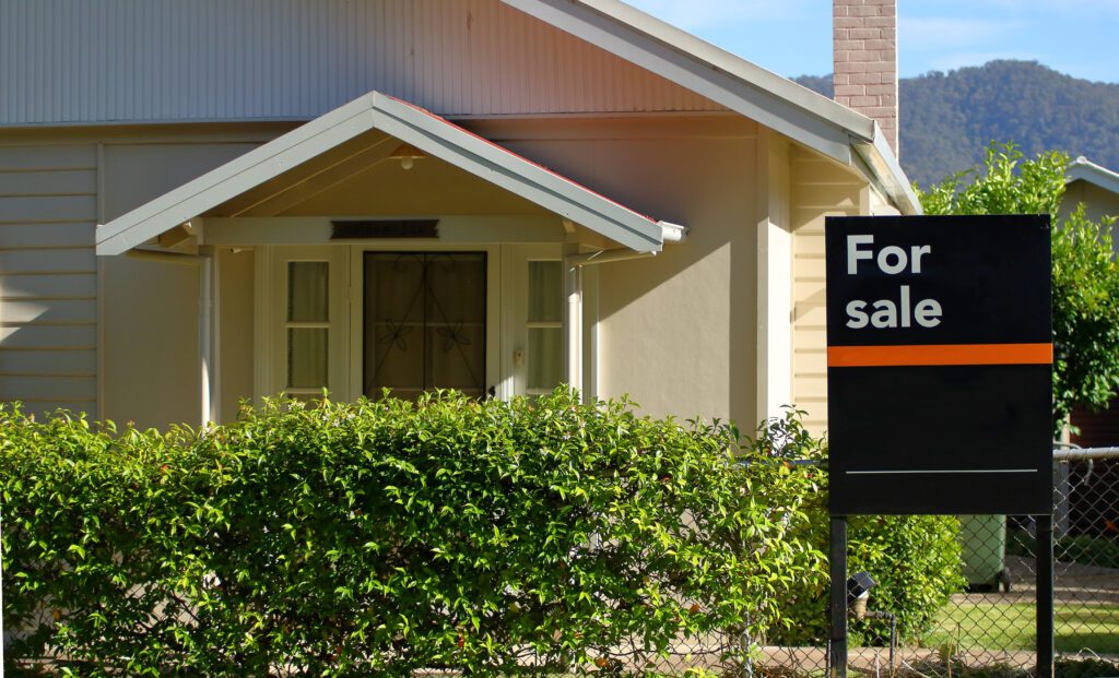 A house with a for sale sign in front of it.